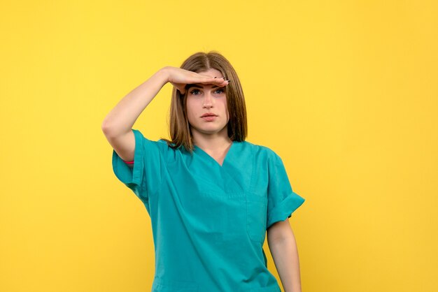 Front view female doctor looking at distance on yellow space