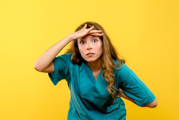 Front view of female doctor looking at distance on yellow wall