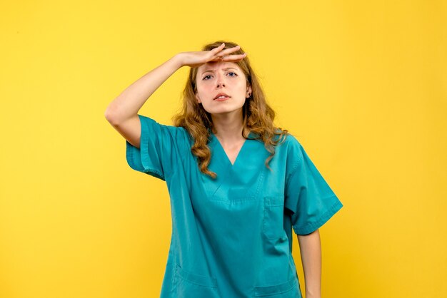 黄色い壁の距離を見ている女性医師の正面図