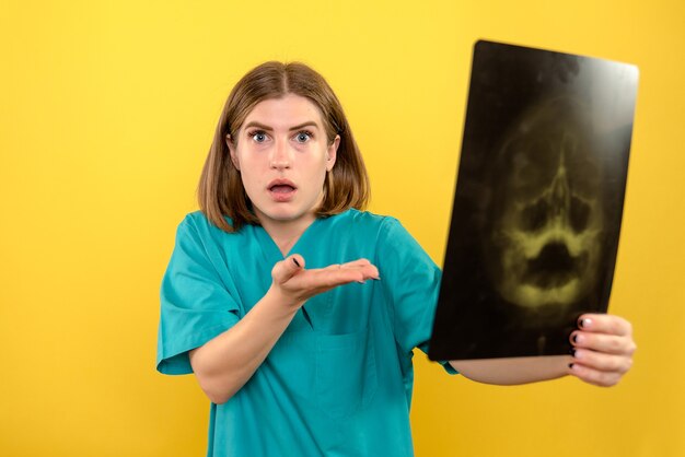 Front view female doctor looking at x-ray on yellow space