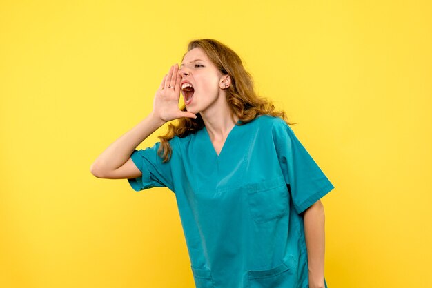 Front view of female doctor loudly calling on yellow wall