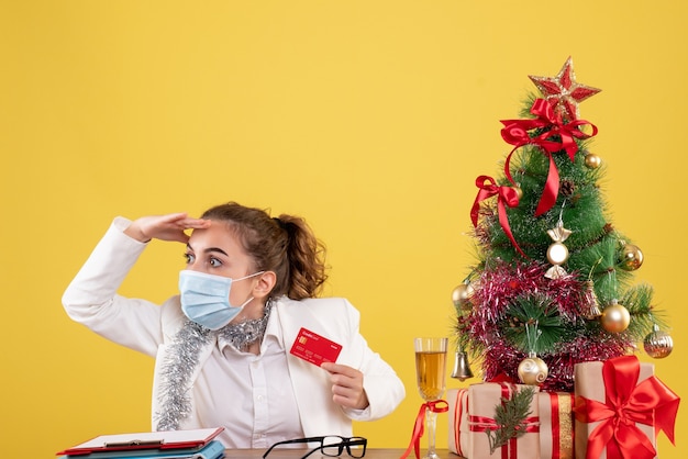 Front view female doctor in mask holding bank card