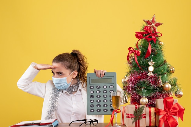 Front view female doctor in mask holding calculator