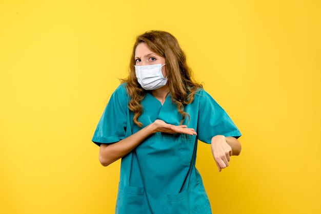 밝은 노란색 공간에 마스크에 전면보기 여성 의사