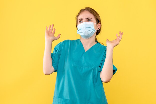 Front view female doctor in mask on yellow background covid- hospital pandemic