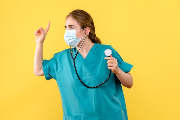 Front view female doctor in mask on yellow background health virus pandemic covid