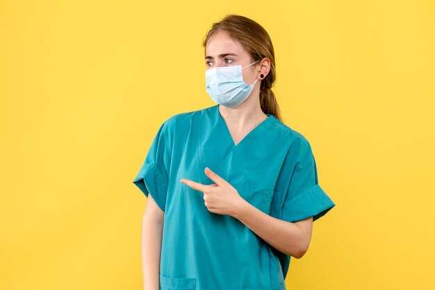 黄色の背景にマスクをした女性医師の正面図病院のパンデミック