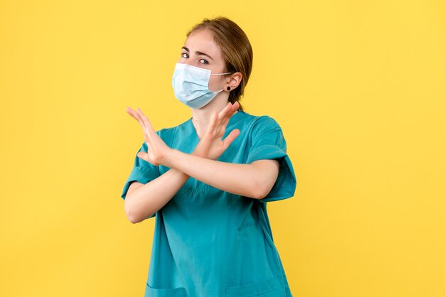 Front view female doctor in mask on yellow desk health hospital covid pandemic