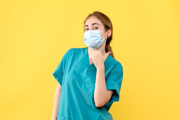 Front view female doctor in mask on yellow desk health hospital pandemic covid