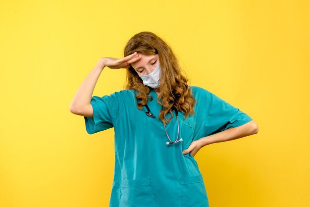 Front view female doctor in mask on a yellow space