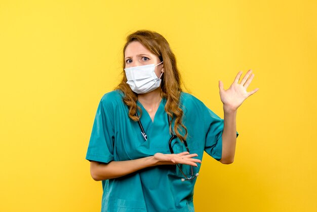 Front view female doctor in mask on a yellow space