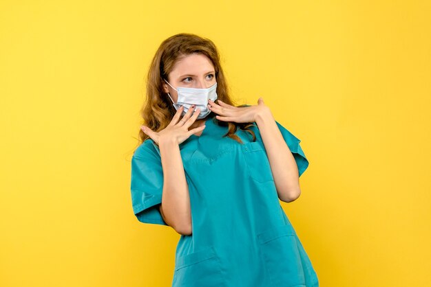 Front view female doctor in mask on a yellow space