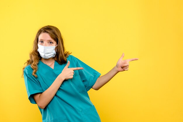 Front view female doctor in mask on a yellow space