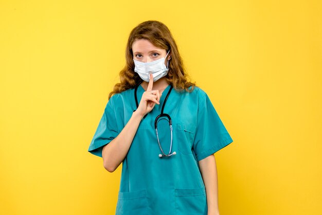 Front view female doctor in mask on the yellow space