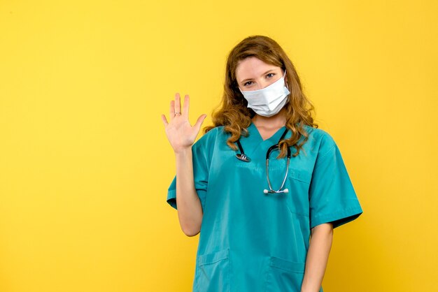 Front view female doctor in mask on the yellow space