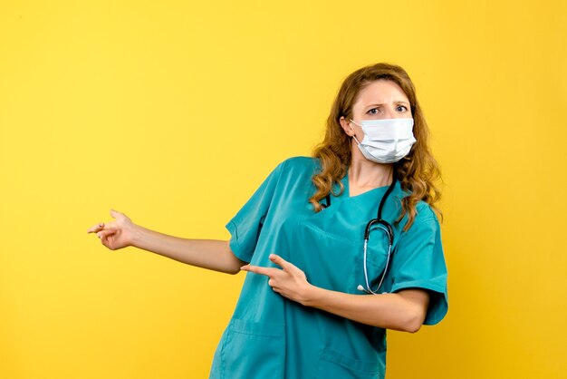 Вид спереди женщина-врач в маске на желтом пространстве