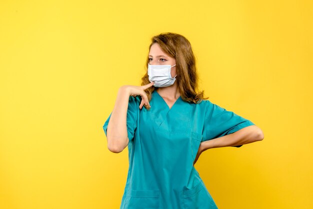 Front view female doctor in mask on the yellow space