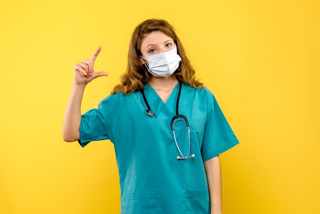 Front view female doctor in mask on a yellow space