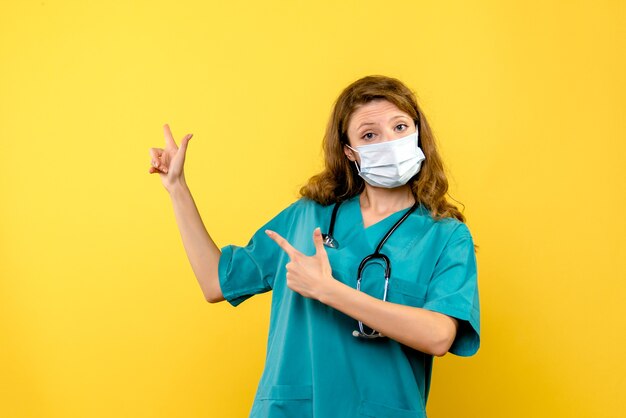Вид спереди женщина-врач в маске на желтом пространстве