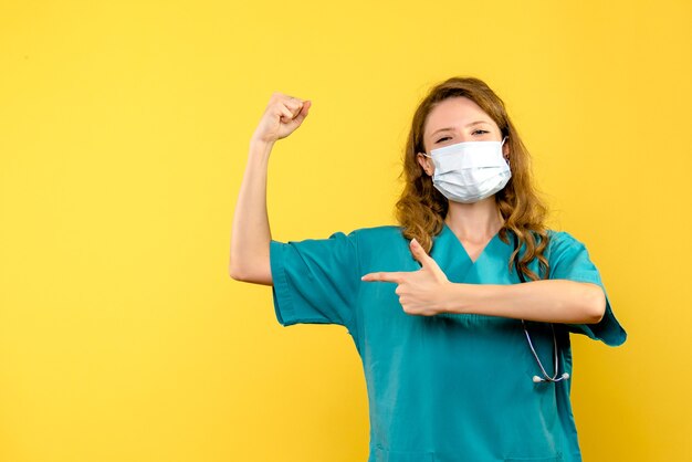 Front view female doctor in mask on yellow space