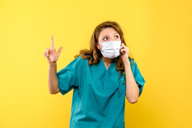 Front view female doctor in mask on yellow space