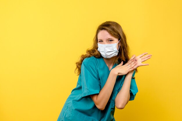 Front view female doctor in mask on yellow space