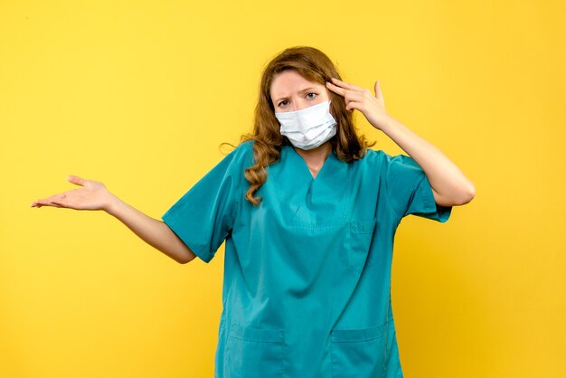Вид спереди женщины-врача в маске на желтой стене