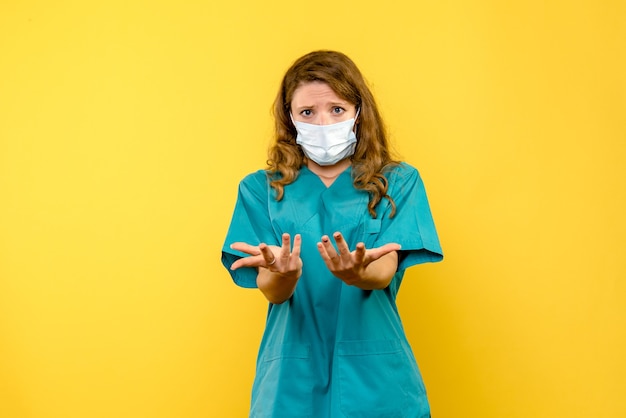 Vista frontale della dottoressa in maschera sulla parete gialla