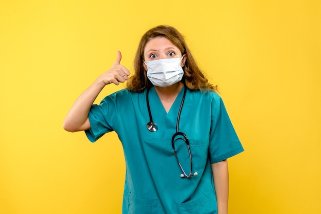 Вид спереди женщины-врача в маске на желтой стене