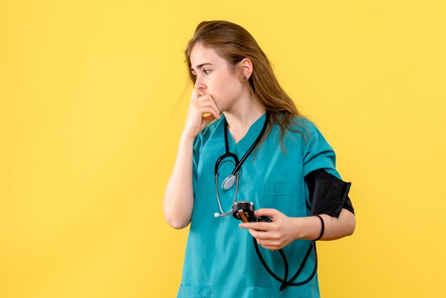 Front view female doctor measuring pressure on light yellow background medic health hospital