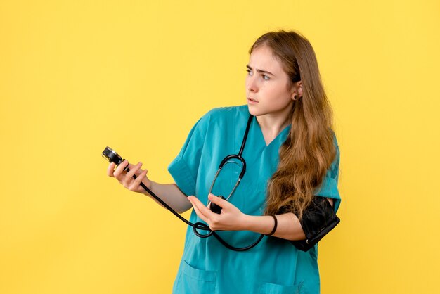 Front view female doctor measuring pressure on yellow background health hospital medic