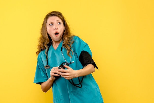 노란색 바닥 병원 건강 의료진에 압력을 측정하는 전면보기 여성 의사