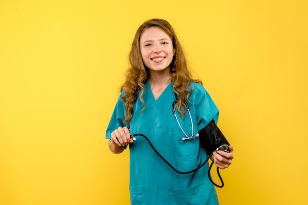 Free photo front view female doctor measuring pressure on a yellow space