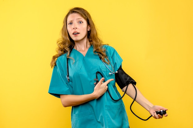 Front view female doctor measuring pressure on yellow space