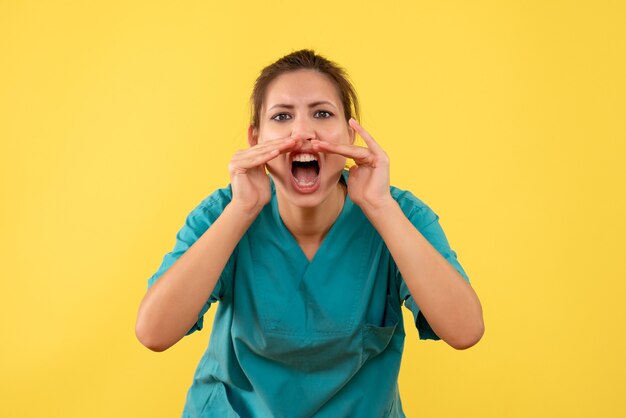 Вид спереди женщина-врач в медицинской рубашке громко звонит на желтом фоне