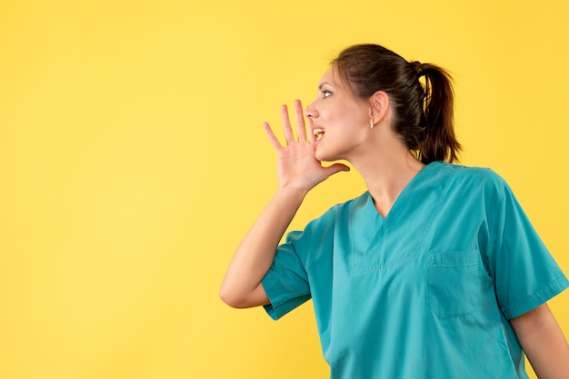 黄色の背景を呼び出す医療シャツの正面の女性医師