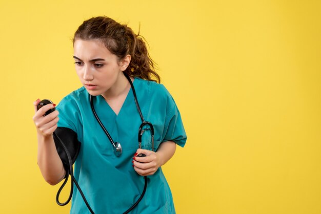 Front view female doctor in medical shirt checking her pressure, virus health emotion uniform covid-