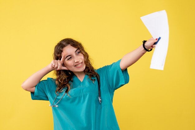 Front view female doctor in medical shirt holding analysis, uniform covid-19 health emotion pandemic virus