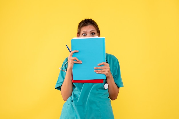 Free photo front view female doctor in medical shirt holding analysis on yellow background