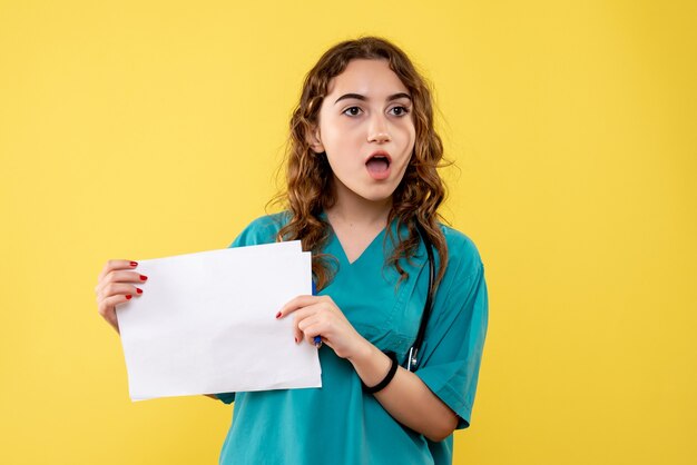 Front view female doctor in medical shirt holding paper analysis, health virus uniform covid-19 pandemic emotion