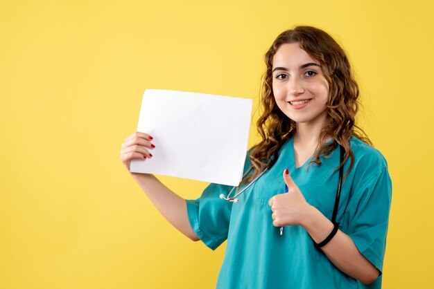 Front view female doctor in medical shirt holding paper analysis, virus pandemic health covid-19 uniform emotion