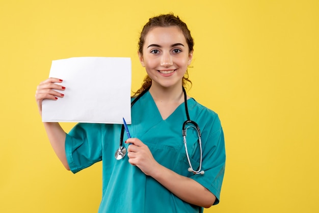 Вид спереди женщина-врач в медицинской рубашке, держащая анализ бумаги, пандемическое здоровье вируса covid-19, униформа эмоций