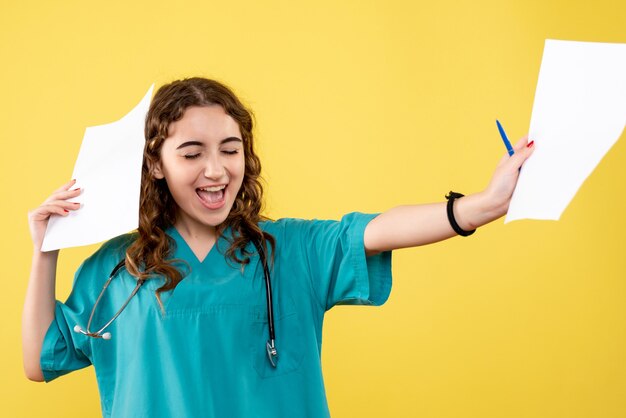 Front view female doctor in medical shirt holding paper analysis, virus uniform covid-19 pandemic emotion