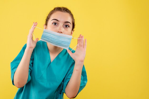 Front view female doctor in medical shirt holding sterile mask, virus uniform color covid-19 health emotion