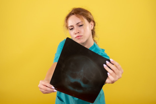 Front view female doctor in medical shirt holding x-ray, color covid-19 health emotion pandemic virus