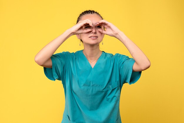 Front view female doctor in medical shirt looking through her fingers, health nurse hospital covid-19 virus color