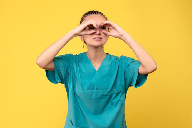 Вид спереди женщина-врач в медицинской рубашке, глядя сквозь пальцы, цвет вируса covid-19 больницы медсестры