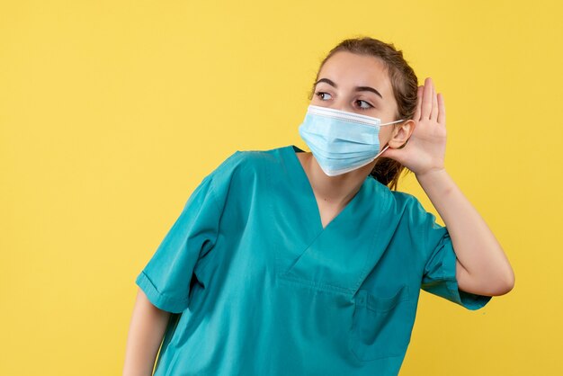 Front view female doctor in medical shirt and mask, health uniform virus covid pandemic color