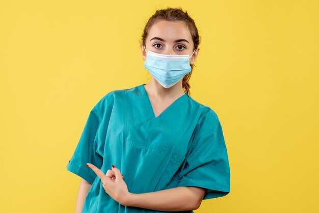 Front view female doctor in medical shirt and mask, health virus covid-19 pandemic color uniform