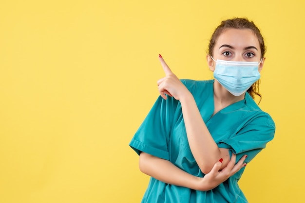 Front view female doctor in medical shirt and mask hurt her hand, color pandemic health virus covid-19 uniform